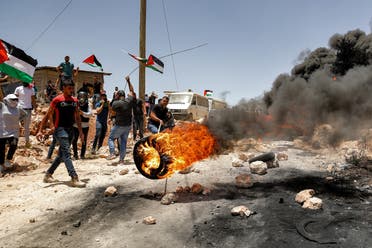 Palestinian protesters set tires aflame during clashes with Israeli security forces following a demonstration in the village of Beita, south of Nablus, in the occupied West Bank on June 11, 2021. (AFP)