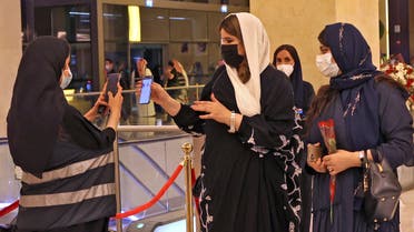 A picture taken late on June 3, 2021 shows Saudi staff checking attendant's mobiles for vaccine certificates or a negative Covid-19 test, at the entrance of a theatre hosting the first concert in the Saudi capital Riyadh since the start of the COVID-19 pandemic. (AFP)