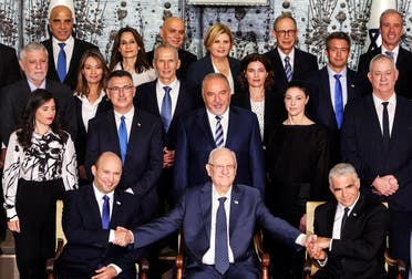 Israel’s President Reuven Rivlin sits next to PM Naftali Bennett and Foreign Minister Yair Lapid as they pose for a group photo with ministers of the new Israeli government, in Jerusalem June 14, 2021. (Reuters/Ronen Zvulun)
