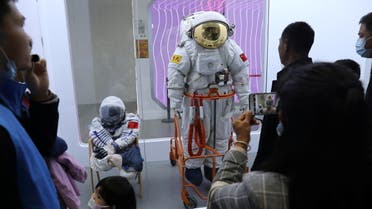 Visitors look at space suits worn by Chinese astronauts from manned space program, at an exhibition featuring the development of China's space exploration on the country's Space Day at China Science and Technology Museum in Beijing, China April 24, 2021. REUTERS/Tingshu Wang