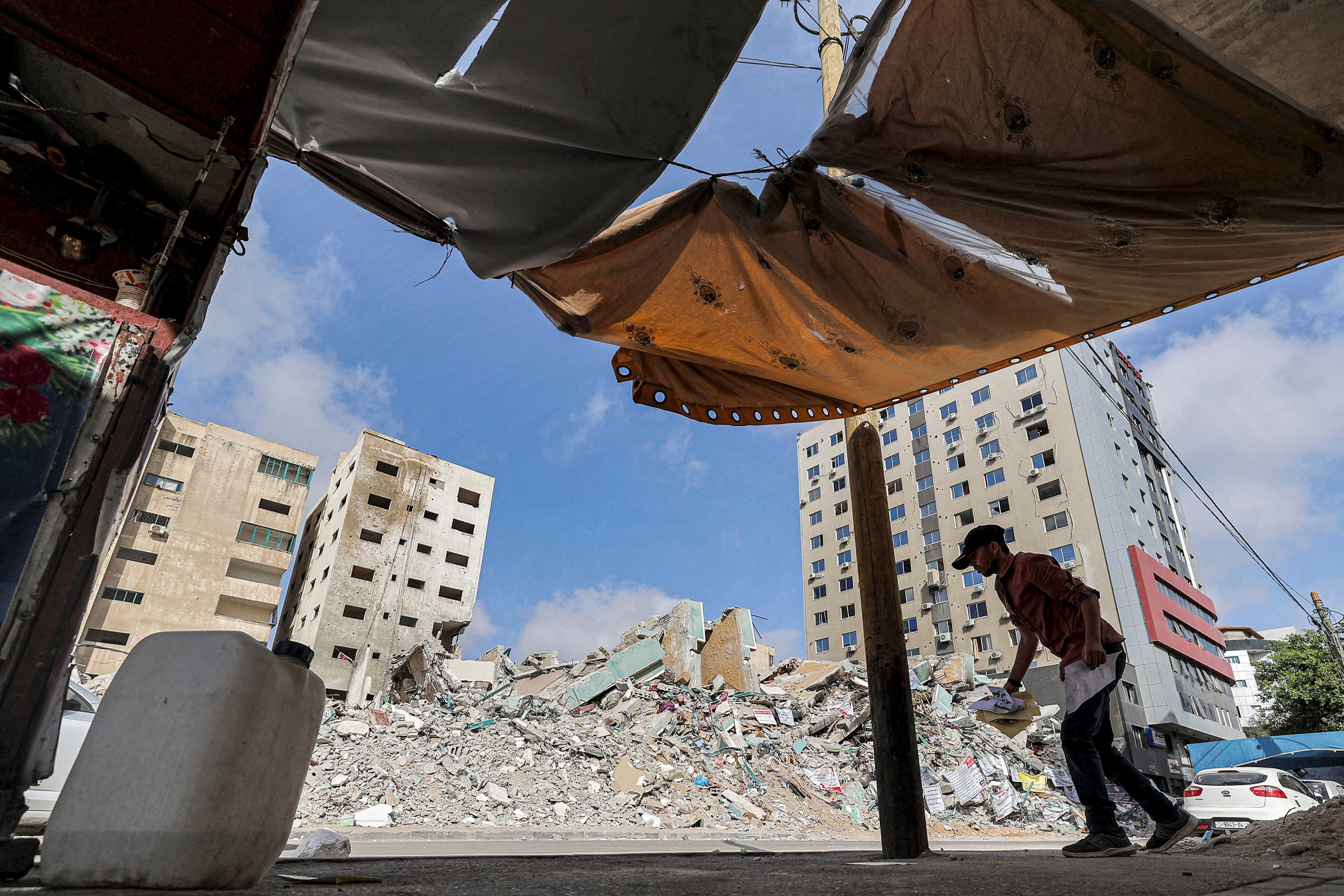 A Palestinian holding fragments of papers walks past the rubble of a building destroyed during the May 2021 conflict between Hamas and Israel in Gaza City's al-Rimal neighbourhood, on June 10, 2021. (AFP)