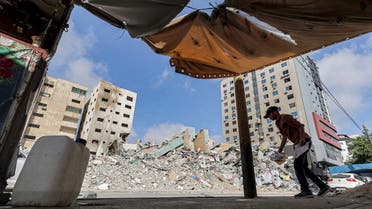 A Palestinian holding fragments of papers walks past the rubble of a building destroyed during the May 2021 conflict between Hamas and Israel in Gaza City's al-Rimal neighbourhood, on June 10, 2021.
