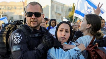 An Israeli policeman removes a Palestinian woman from the area as youth from far-right Israeli groups participate in a flag-waving procession at Damascus Gate, just outside Jerusalem’s Old City June 15, 2021. (Reuters/Ammar Awad)