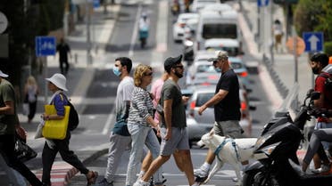 Pedestrians cross a street as Israel rescinds the mandatory wearing of face masks outdoors in the latest return to relative normality, boosted by a mass-vaccination campaign against the coronavirus disease (COVID-19) pandemic, in Tel Aviv, Israel April 18, 2021. (Reuters)