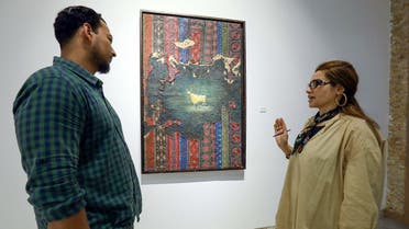 A visitor talks to Libyan artist Elham el-Ferjani in front of one of her works at the Hamim Gallery in the eastern city of Benghazi on June 14, 2021. (Abdullah Doma/AFP)