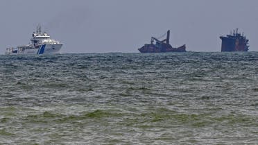 An Indian Coast Guard ship (L) approaches near the Singapore-registered container ship MV X-Press Pearl that partially sunk after burning for almost two weeks, just outside Colombo’s harbor on June 4, 2021. (Lakruwan Wanniarachchi/AFP)