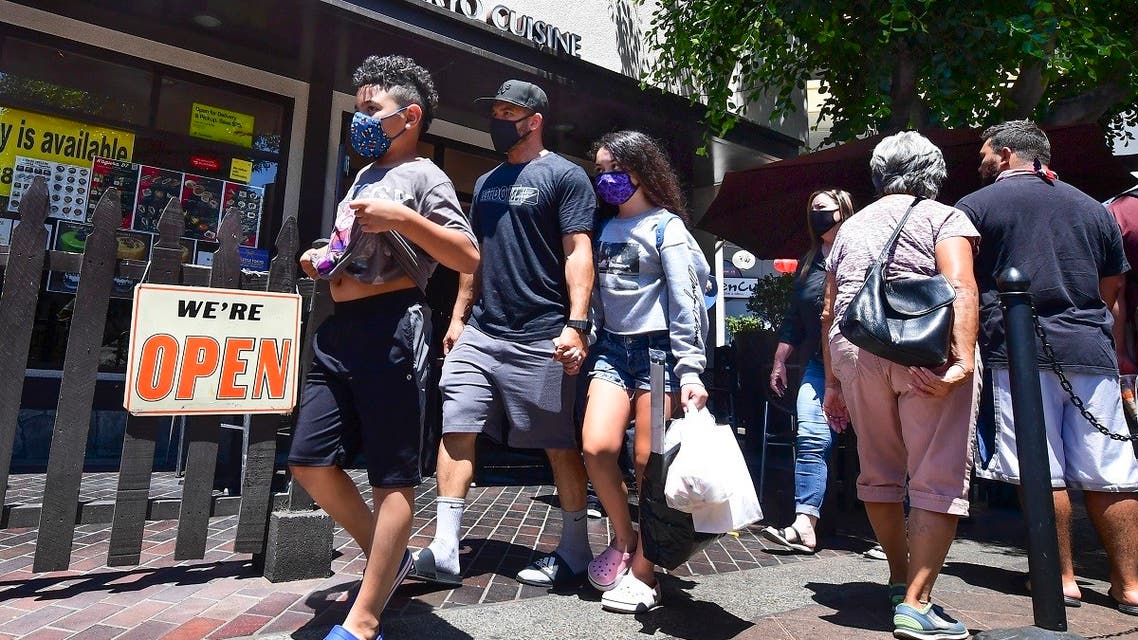 Face masks continue to be worn as people walk past restaurants open for business in Los Angeles on June 14, 2021. (Frederic J. Brown/AFP)