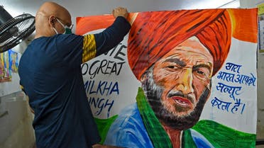 An art teacher holds a painting of Indian track legend Milkha Singh at his studio in Mumbai on June 19, 2021. (Punit Paranjpe/AFP)
