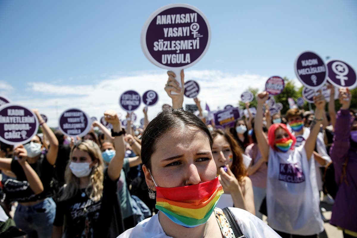 Activists hold signs during a protest against Turkey's withdrawal from the Istanbul Convention, an international accord designed to protect women, in Istanbul, Turkey, June 19, 2021. The sign in the centre reads: Enforce the constitution, law and convention. (Reuters)