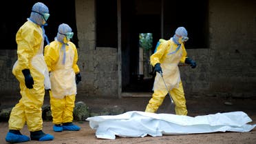 (FILES) In this file photo taken on November 19, 2014 Health workers from Guinea's Red Cross prepare to carry the body of a victim of the Ebola virus in Momo Kanedou in Guinea . The World Health Organization on June 19, 2021 officially announced the end of Guinea's second Ebola outbreak which was declared on February 14. AFP