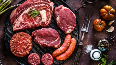 Various cuts of raw meat shot from above on a cast iron grill stock photo