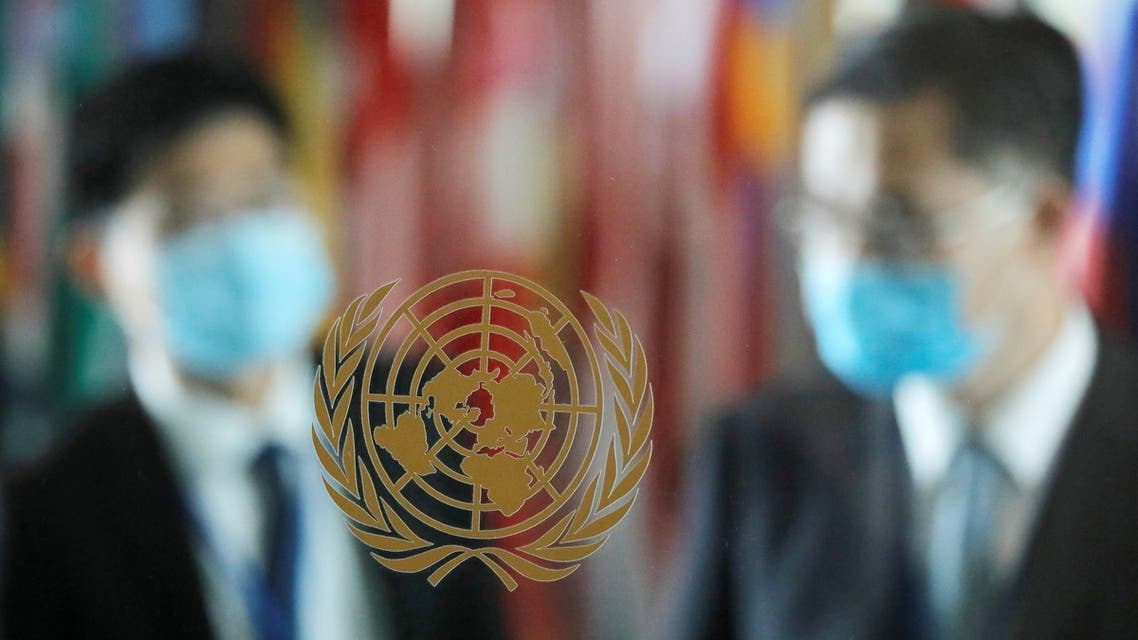 People wearing face masks are seen behind the emblem of the United Nations at its headquarters. (Reuters)