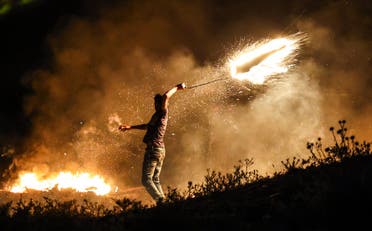 متظاهر فلسطيني يلقي قذيفة مشتعلة على الحدود مع إسرائيل - أرشيفية