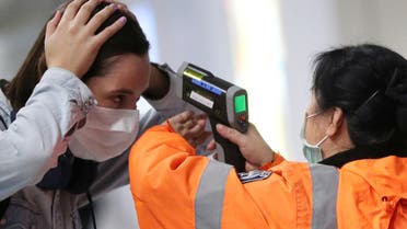 A worker checks the temperature of a passenger arriving into Hong Kong International Airport with an infrared thermometer, following the coronavirus outbreak in Hong Kong, China, February 7, 2020. REUTERS/Hannah McKay