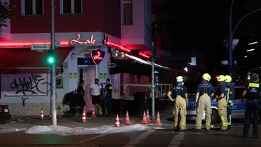 Firemen and policemen stand at the crime scene in front of a Shisha Bar in Berlin on June 21, 2021, after four persons were hit by shots fired from a car that was driving by. (AFP)
