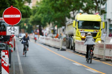 People ride on bicycles as workers build bicycle lanes in the Bergmannstrasse in Berlin, Germany, on June 22, 2021. (Reuters)