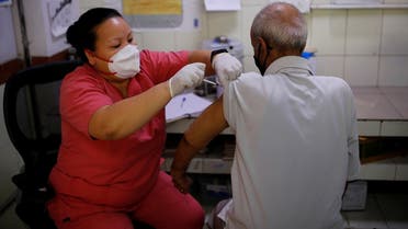 Kailash Nath, 69, receives a dose of COVISHIELD vaccine, a coronavirus vaccine, manufactured by Serum Insitutue of India, after he was helped by a volunteer from SEEDS, an NGO which normally specialize providing relief after floods and other natural disasters, to reach the vaccination center, in New Delhi, India. (Reuters)  