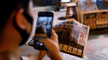 A man takes a photo of his copy of the Apple Daily newspaper after it looked set to close for good by Saturday following police raids and the arrest of executives in Hong Kong, China June 22, 2021. (Reuters)
