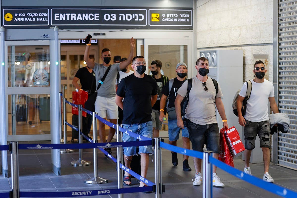 Vaccinated tourists wearing masks for COVID-19 protection arrive to Israel’s Ben Gurion Airport near Tel Aviv on May 23, 2021, after a partial re-opening of the border to inoculated tourists from 14 countries. (AFP)
