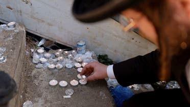 An ultra-Orthodox Jewish man lights candles at the site where dozens were crushed to death in a stampede at a religious festival, as the country observes a day of mourning, at Mount Meron, Israel May 2, 2021. (Reuters)