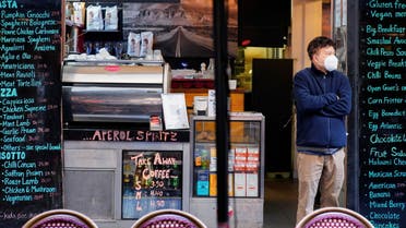A man wearing a protective face mask stands at the entrance of a cafe on the first day of eased coronavirus disease (COVID-19) restrictions for the state of Victoria following an extended lockdown in Melbourne, Australia, June 11, 2021. (REUTERS)