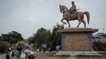 Passengers walk next to the statue of Alula Aba Nega, Ethiopian general from Tigray, after flights to Addis Ababa was cancelled at Mekelle airport in Mekele, the capital of Tigray region, Ethiopia, on June 25, 2021. (AFP)