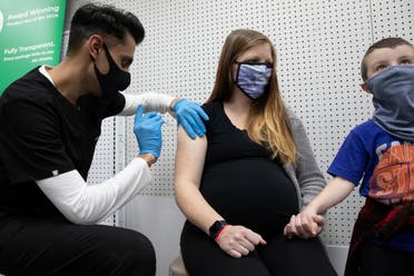 Aubrie Cusumano, who is 39 weeks pregnant, receives the Pfizer-BioNTech vaccine against the coronavirus disease (COVID-19) while holding her son, Luca's hand at Skippack Pharmacy in Schwenksville, Pennsylvania, US, February 11, 2021. (Reuters)