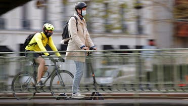 A man, wearing a protective face mask, rides a scooter past a biker on a bridge over the canal Saint-Martin in Paris amid the coronavirus (COVID-19) outbreak in France, April 22, 2021. (Reuters)