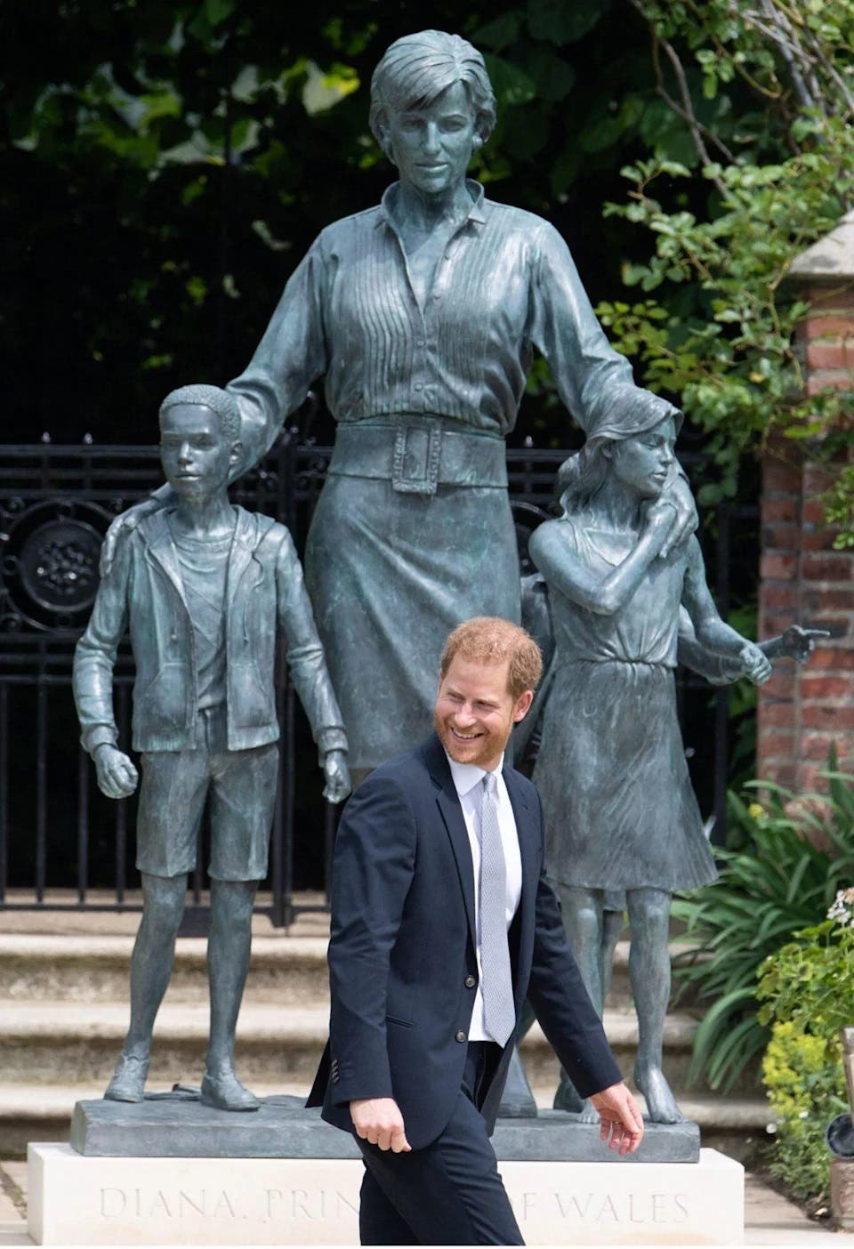 Prince Harry smiling in front of the statue