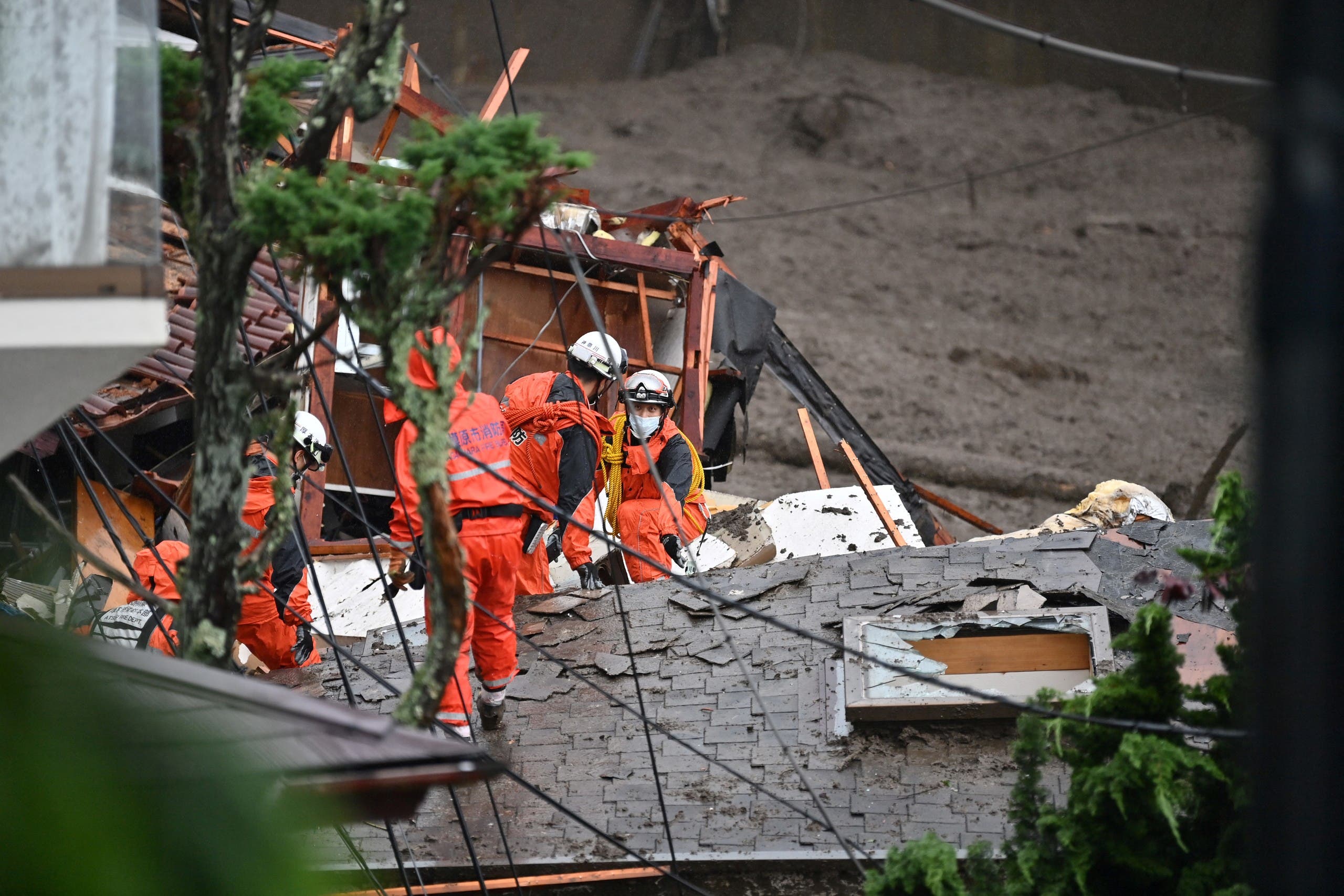 Firefighters search for missing people at the scene of a landslide following days of heavy rain in Atami in Shizuoka Prefecture on July 4, 2021. A huge landslide swept away homes and left 19 people missing at a popular resort town in central Japan on July 3 after days of heavy rain, local officials said.