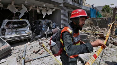 In this June 23, 2021 file photo, a rescue worker examines the site of explosion in Lahore, Pakistan. In a news conference Sunday, July 4, 2021, in Islamabad, Moeed Yousuf, Pakistanâ€™s national security advisor, accused India of orchestrating teh June 23 deadly car bombing in the eastern city of Lahore, saying that an investigation has shown it was organized by an unnamed Indian intelligence operative. (AP Photo/K.M. Chaudary, File)