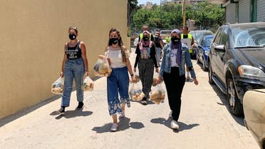 Volunteers from Base Camp, walk as they carry bags of vegetables to be distributed to people in need in Beirut, Lebanon July 1, 2021. (Reuters)