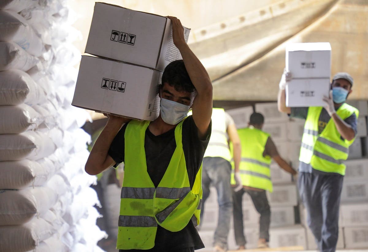 Workers carry boxes of humanitarian aid near Bab al-Hawa crossing at the Syrian-Turkish border, in Idlib governorate, Syria, on June 30, 2021. (Reuters)