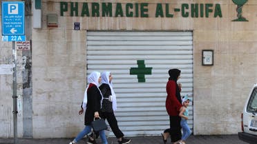 People walk in front of the shuttred door of a pharmacy in the Lebanese capital Beirut, during a nationwide strike of pharmacies to protest against a severe shortage of medicine, on July 9, 2021. (File photo: AFP)