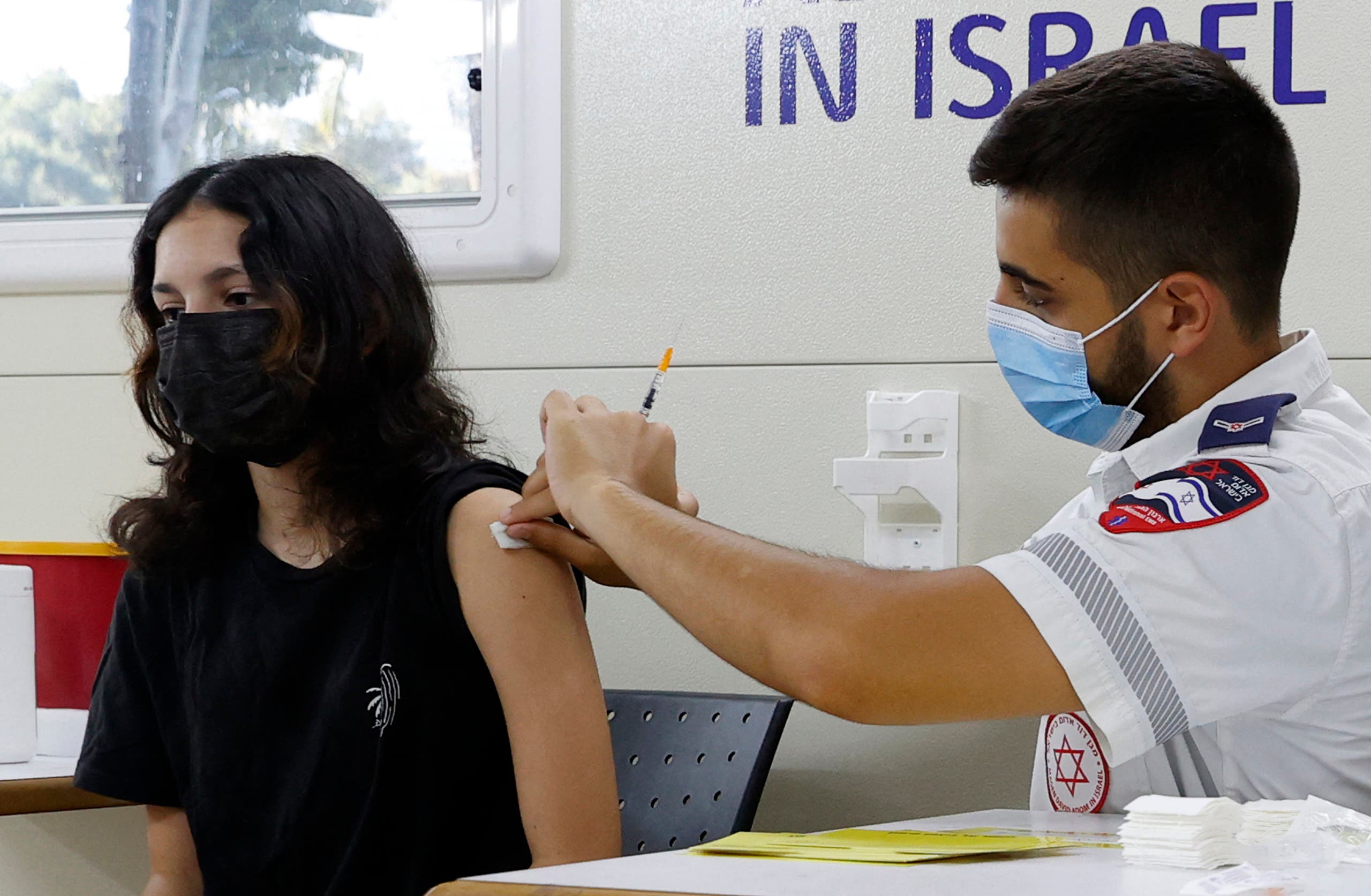 An Israeli girl receives a dose of the Pfizer/BioNTech COVID-19 vaccine from the Magen David Adom during a campaign by the Tel Aviv-Yafo Municipality to encourage the vaccination of teenagers, on July 5, 2021, in Tel Aviv. (AFP)
