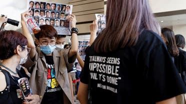 Supporters hold up placards among people queuing up at the West Kowloon Magistrates’ Courts for a hearing of 47 pro-democracy activists charged with violating the national security law, in Hong Kong, on July 8, 2021. (Reuters)