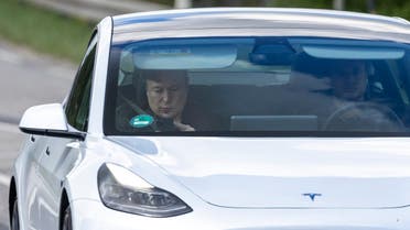 Tesla CEO Elon Musk (L) is seen as he uses his mobile device in the car arriving to the construction site for the new plant, the so-called Giga Factory, of US electric carmaker Tesla, in Gruenheide near Berlin, northeastern Germany. (AFP)