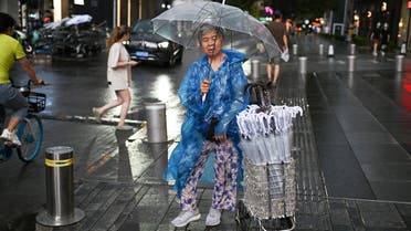 A woman sells umbrellas outside a shopping mall after a rain shower in Beijing on July 8, 2021. (File photo: AFP)
