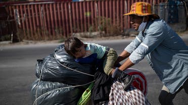 An Afghan migrant pushes a cart with his son and their belongings, following a fire at the Moria camp on the island of Lesbos, Greece, September 11, 2020. (Reuters)