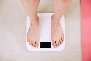 Person standing on white digital scale to measure their body weight. (Unsplash, Yunmai)
