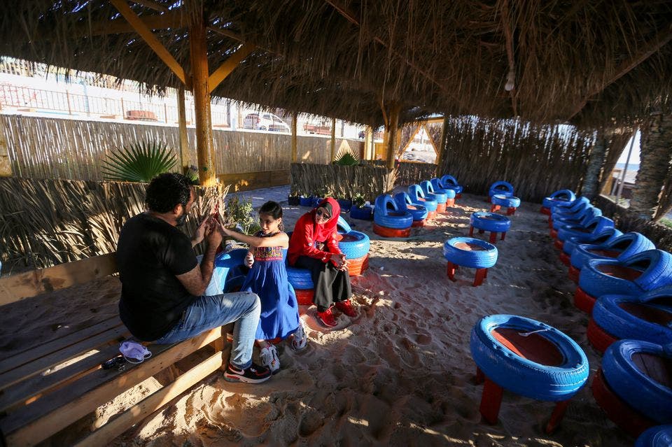 Palestinian beachgoers sit on chairs that have been made of car tires at an environment-friendly beachfront cafe in Gaza, on July 8, 2021. (Reuters)