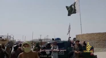 People stand in front of a vehicle as an Islamic Emirate of Afghanistan and a Pakistan's flag flutter in front of the friendship gate of Afghanistan and Pakistan at the Wesh-Chaman border crossing, Spin Boldak, Afghanistan July 14, 2021, in this screen grab obtained from a video. (Reuters)