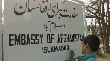 A young painter writes a new sign for the Afghan embassy in the Pakistan capital Islamabad February 13, 2002. (Reuters)