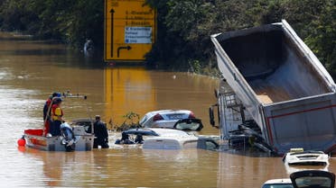 A police officer and a member of the Bundeswehr forces look at partially submerged cars on a flooded road following heavy rainfalls in Erftstadt-Blessem, Germany, July 17, 2021. REUTERS/Thilo Schmuelgen