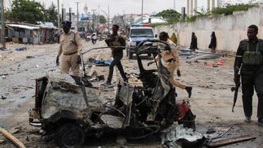 Police officers patrol by the wreckage of a car at the scene of suicide car bomb attack that targeted the city's police commissioner in Mogadishu, on July 10, 2021. (AFP)