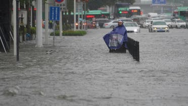 A resident wearing a rain cover stands on a flooded road in Zhengzhou, Henan province, China July 20, 2021. cnsphoto via REUTERS ATTENTION EDITORS - THIS IMAGE WAS PROVIDED BY A THIRD PARTY. CHINA OUT.