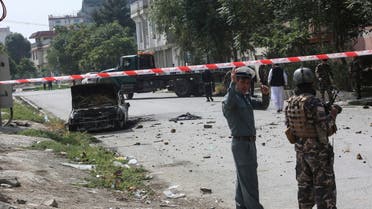 Afghan security personnel stand guard near a charred vehicle from which rockets were fired that landed near the Afghan presidential palace in Kabul on July 20, 2021.