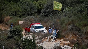 UN peacekeepers stand next to a Hezbollah flag raised on the Lebanese side of the border fence with Israel, near the northern Israeli settlement of Shtula on July 20, 2021. (AFP)