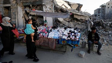 A Palestinian sells socks on a stall near the rubble of his old store that has been destroyed in an Israeli air strike, ahead of Eid Al-Adha holiday, in Gaza City, on July 14, 2021.  (Reuters)