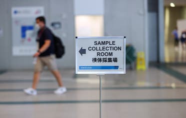 A sign is seen as a man walks to the PCR sample collection room at the main press center ahead of the Tokyo 2020 Olympic Games that were postponed to 2021 due to the coronavirus disease (COVID-19) pandemic, in Tokyo, Japan, July 22, 2021. (Reuters)